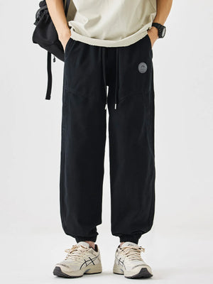 Black relaxed fit drawstring lounge pants with elastic cuffs and a logo patch.
