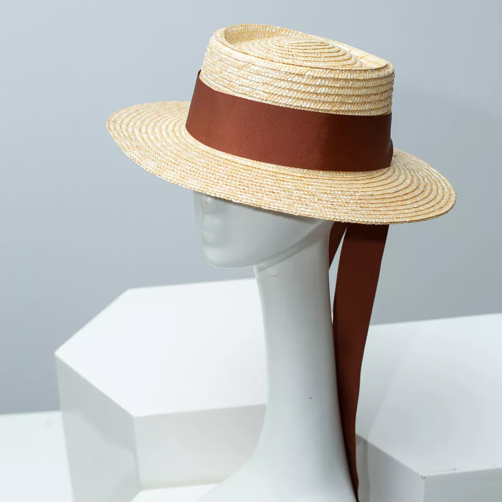Classic straw boater hat with coffee ribbon and long trailing tie.
