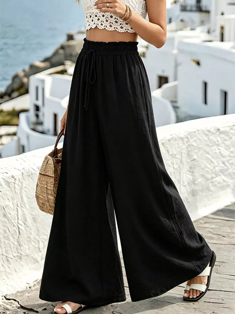 Black wide-leg linen pants with drawstring waist and ruffled detail