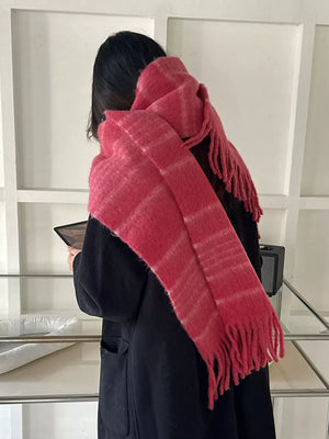 Pink plaid scarf with fringe hem detail, worn by a person in a black coat.