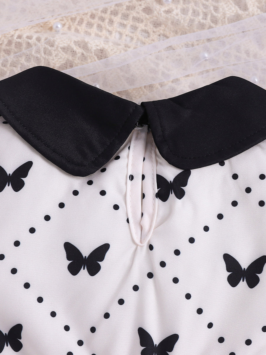 Baby dress with black collar, white fabric, and black butterfly & polka dot print.