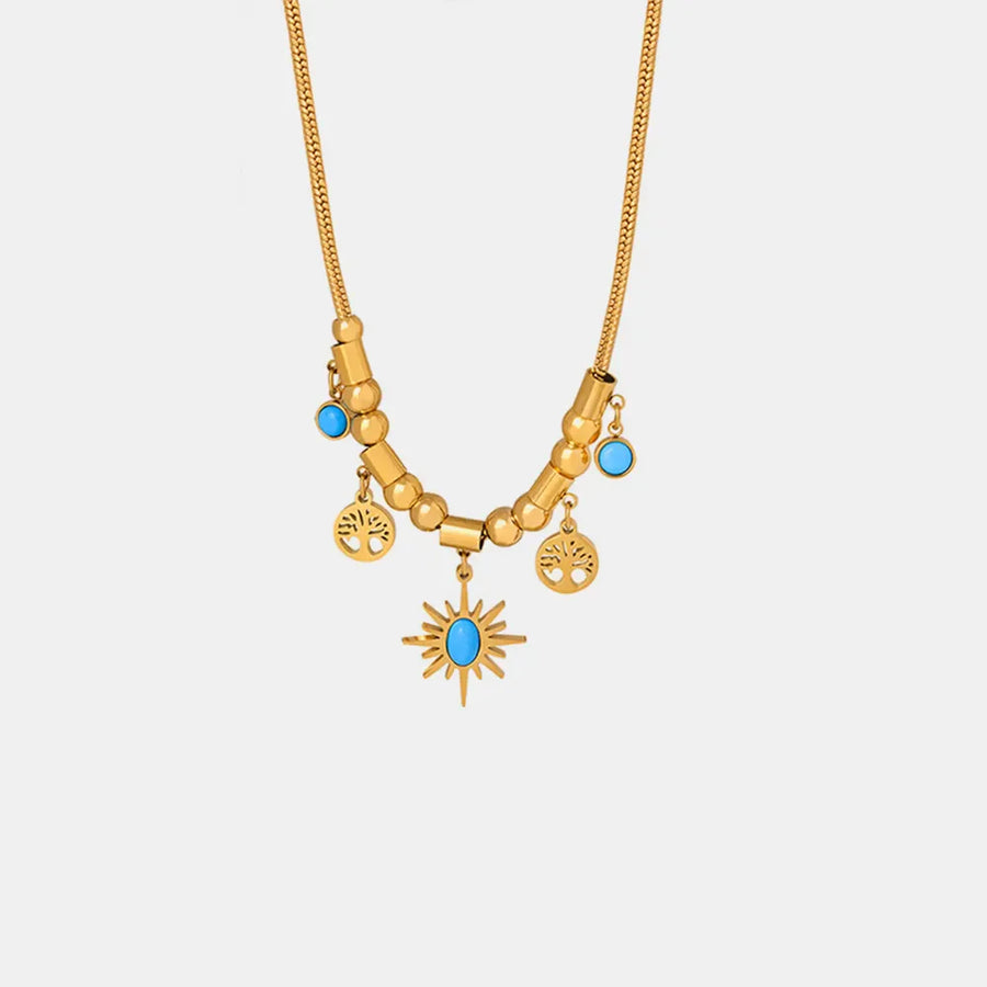 Gold celestial charm necklace with sunburst pendant, tree charms and turquoise accents