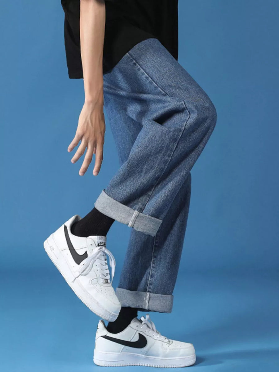 Men's relaxed fit cuffed hem jeans in light wash denim, styled with white sneakers.