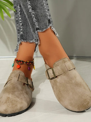 Beige textured suede mules with buckle detail and cork sole.