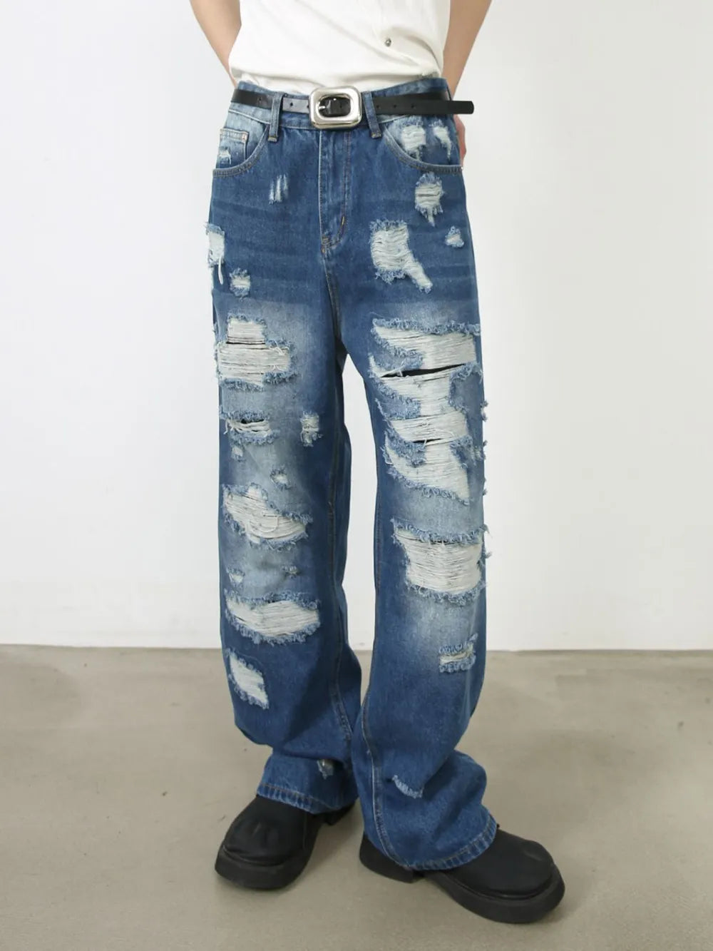 Oversized ripped denim jeans in medium wash with raw edge details and distressed accents.