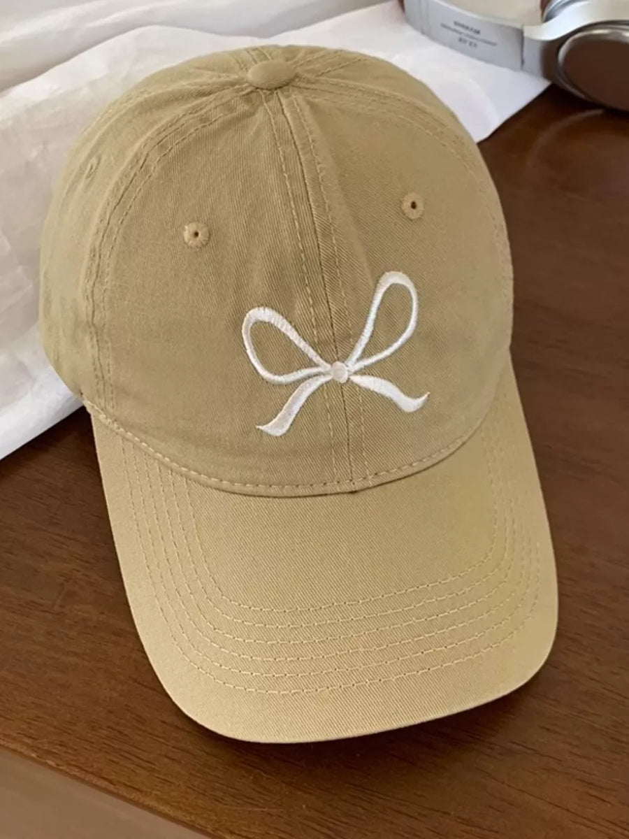 Tan baseball cap with white embroidered bow detail