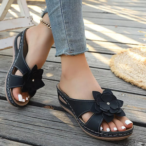 Black floral embellished mid-wedge sandals with white stitching detail.