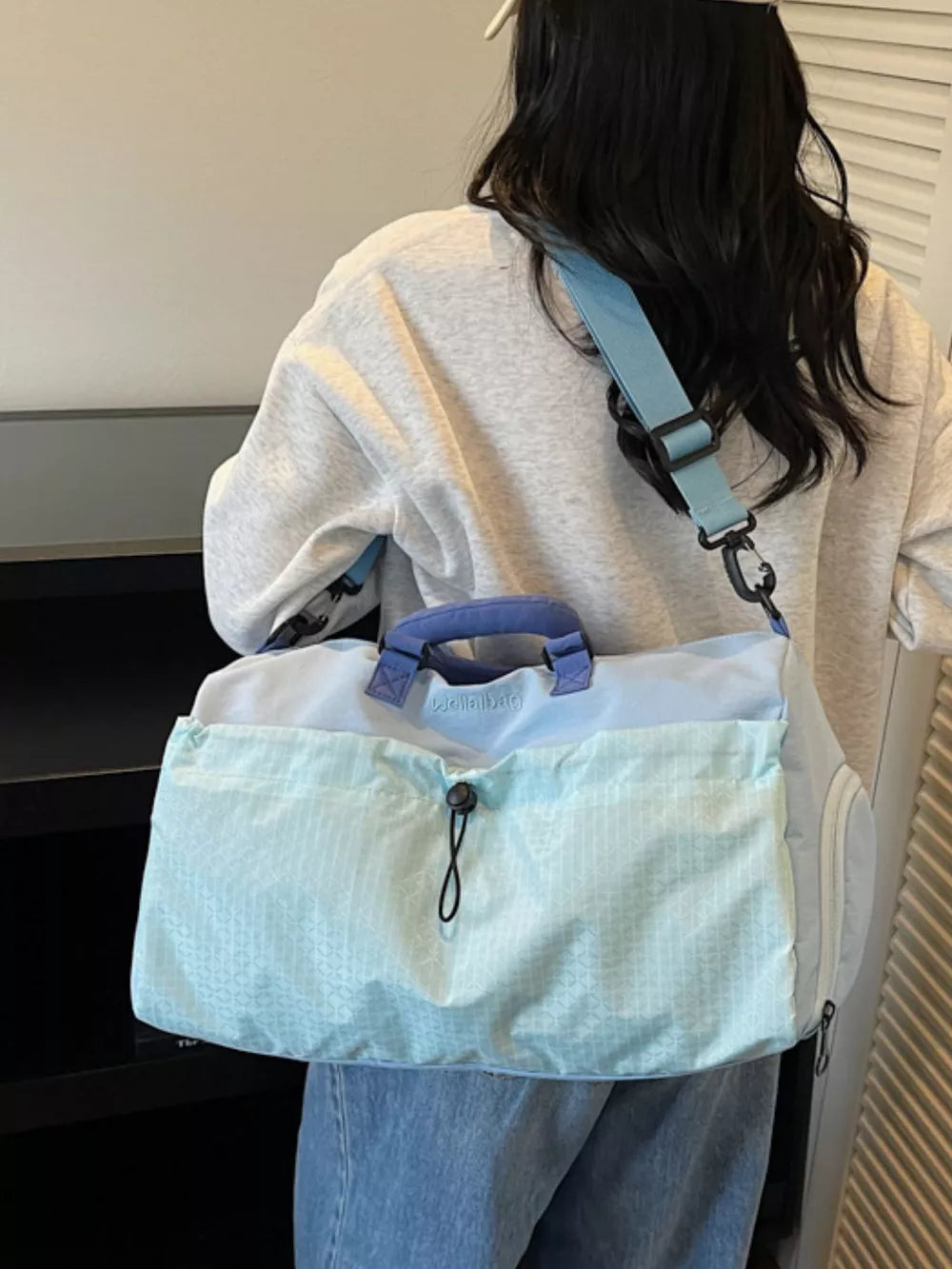 Chic two-tone aqua nylon travel bag with detachable strap and patterned front pocket.