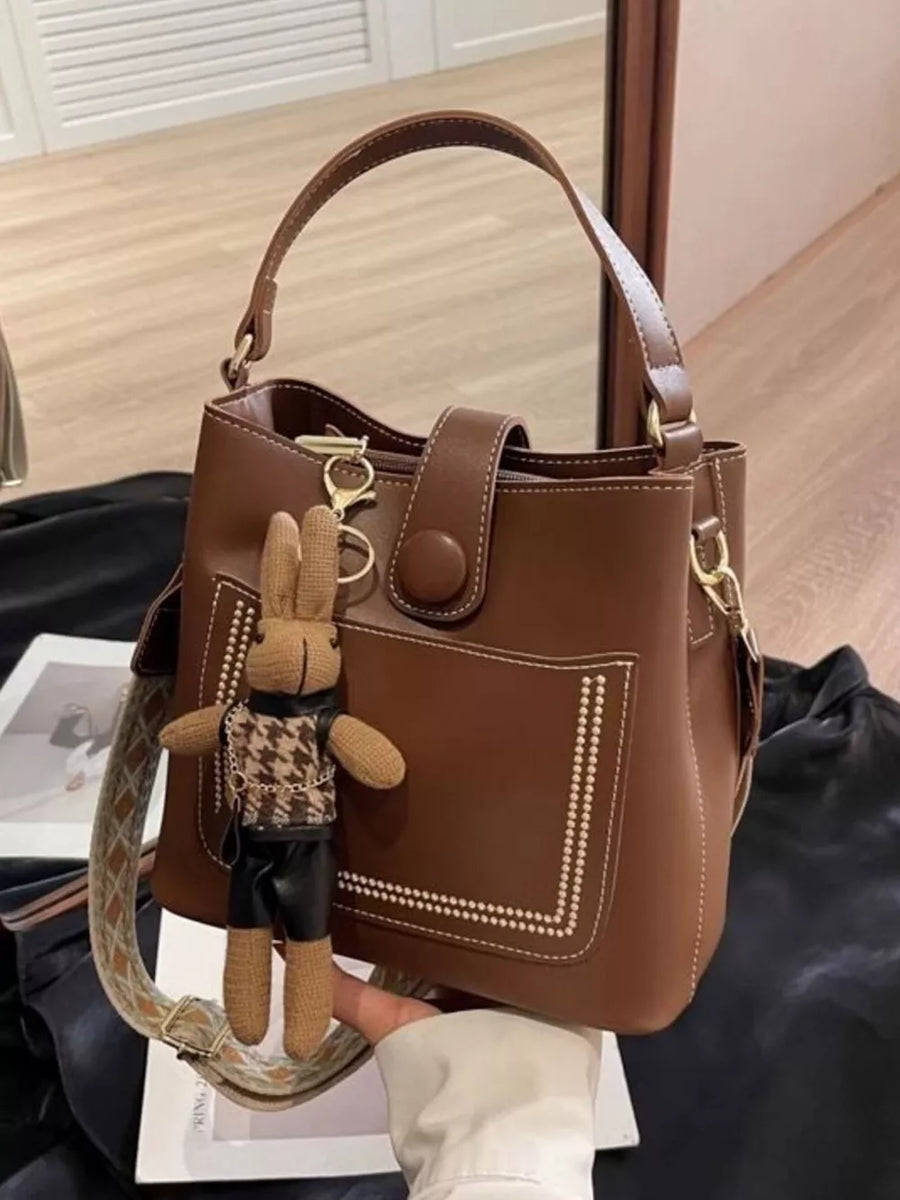 Brown pu leather bucket crossbody bag with decorative stitching and bunny charm
