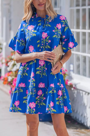 Blue tiered cotton dress with pink floral print, ruffled sleeves, and tie neckline.