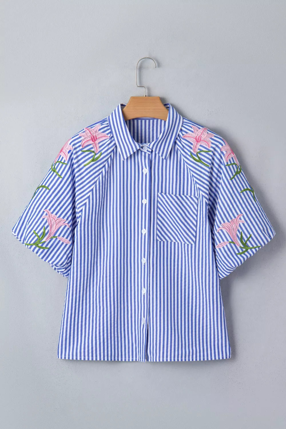 Blue and white striped button-down shirt with pink floral embroidery on the sleeves and shoulders.