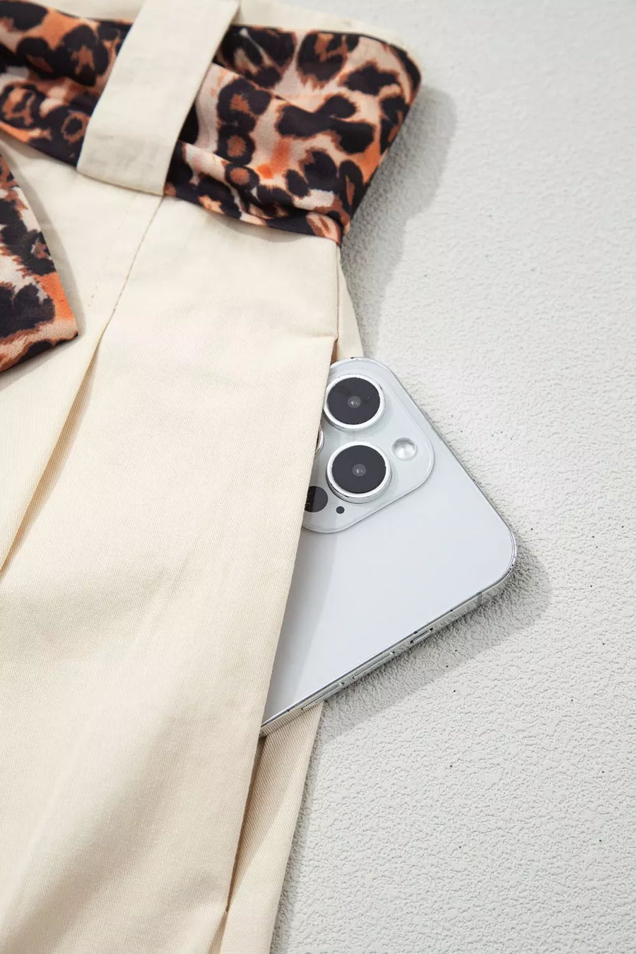 Cream linen blend shorts with leopard print trim and a phone in the pocket.
