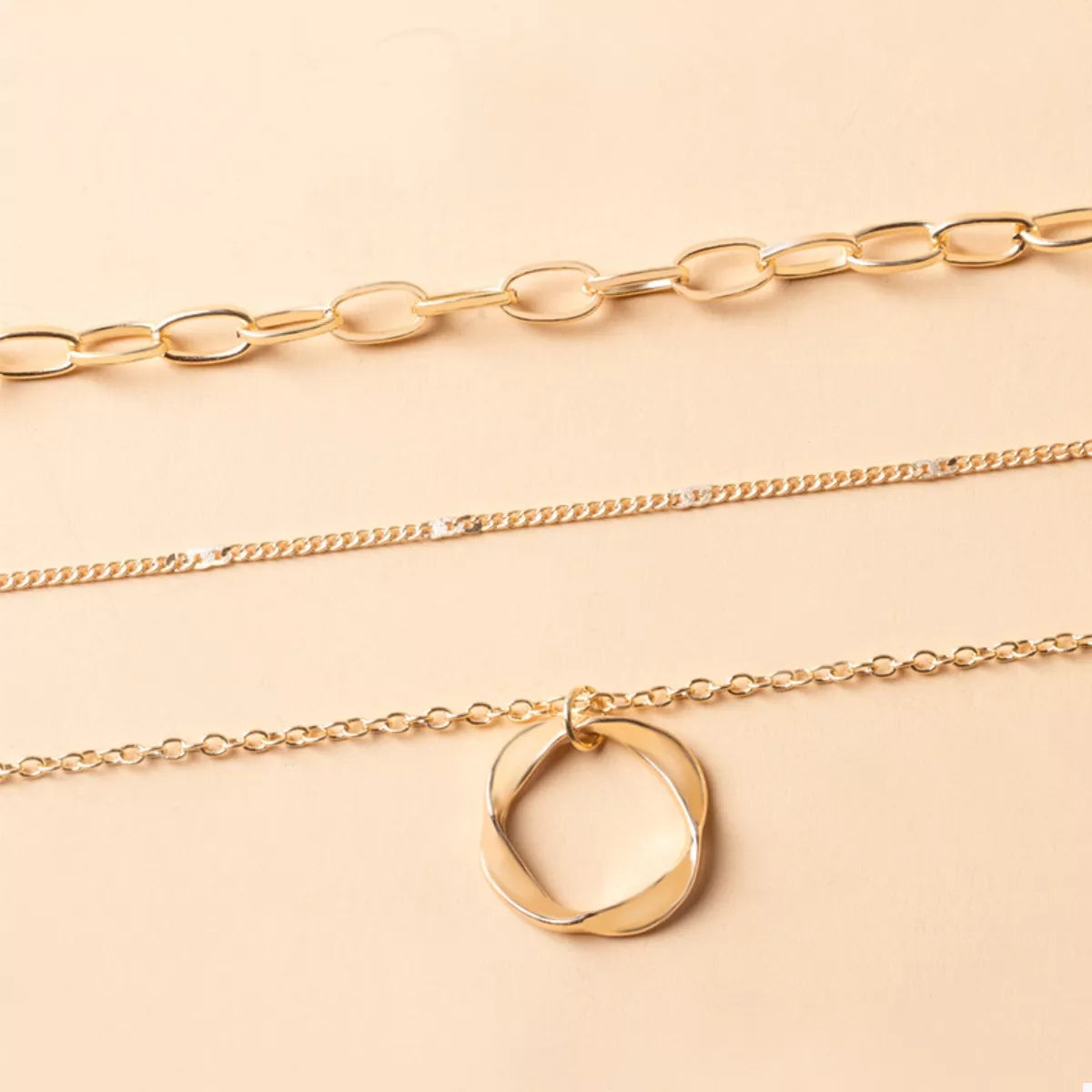 Gold layered necklace with a twisted circle pendant and delicate chains.
