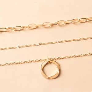 Gold layered necklace with a twisted circle pendant and delicate chains.