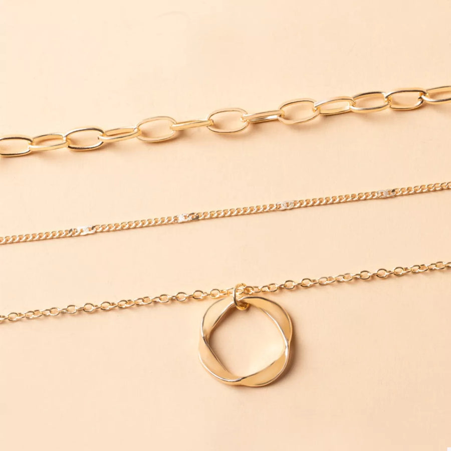 Gold layered necklace with a twisted circle pendant and delicate chains.