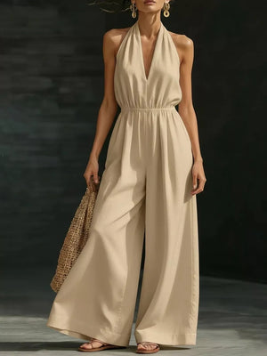 Apricot halter jumpsuit with wide legs and elastic waist, styled with sandals and a straw bag.