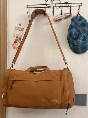 Caramel oxford cloth travel bag with detachable strap and front pocket detail.