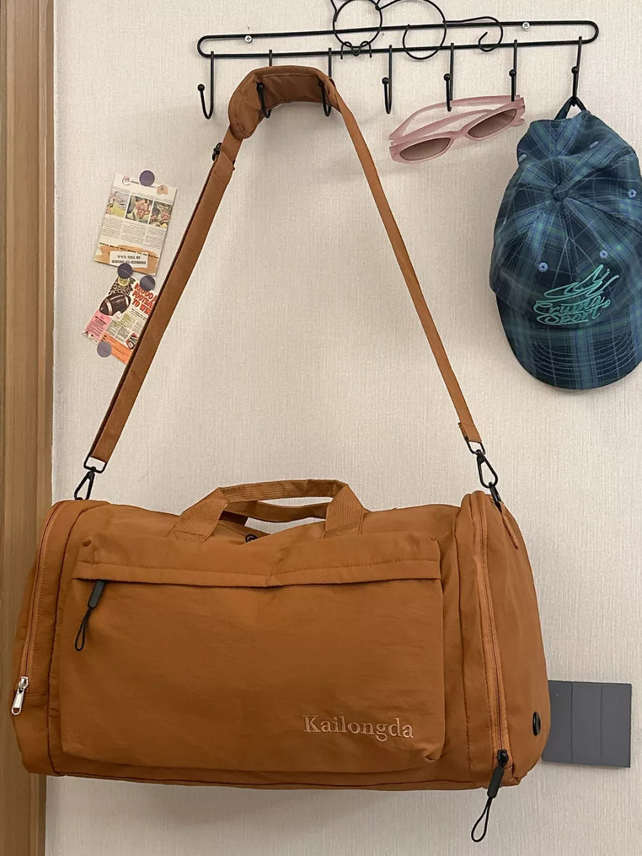 Caramel oxford cloth travel bag with detachable strap and front pocket detail.