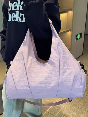 Light purple nylon duffel bag with ruched detailing and a wide shoulder strap.