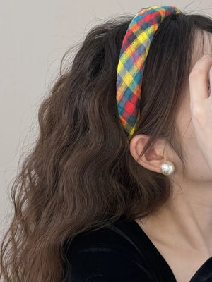 Padded headband with multicolor plaid woven fabric and a knot detail.