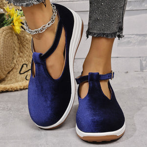 Blue velvet T-bar flat slip-ons with adjustable ankle strap and white sole.