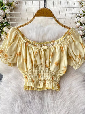 Yellow floral print crop top with smocked waist, ruffled hem, tie front, and puff sleeves.