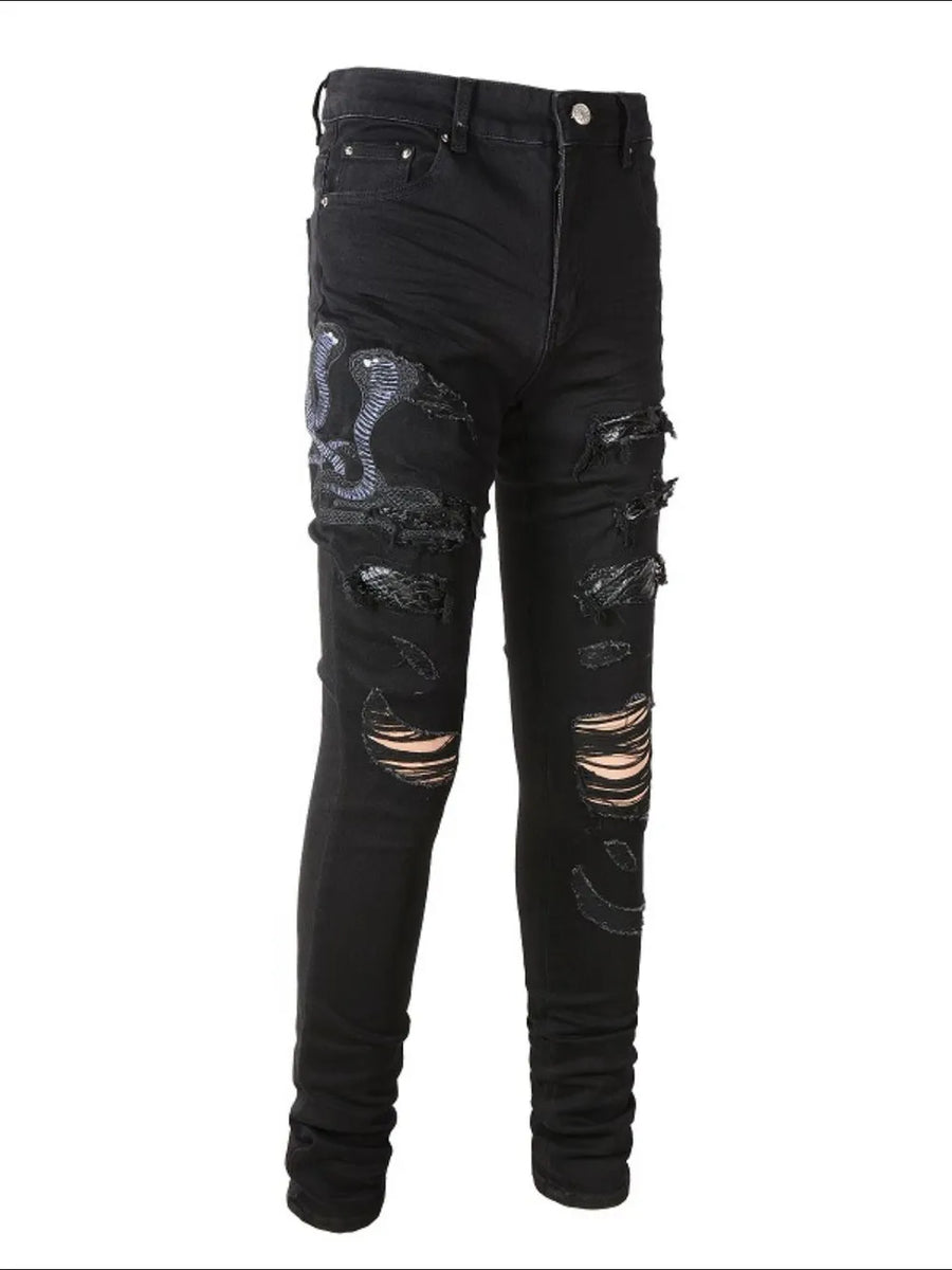 Black skinny jeans with embroidered cobra detail and distressed rips.