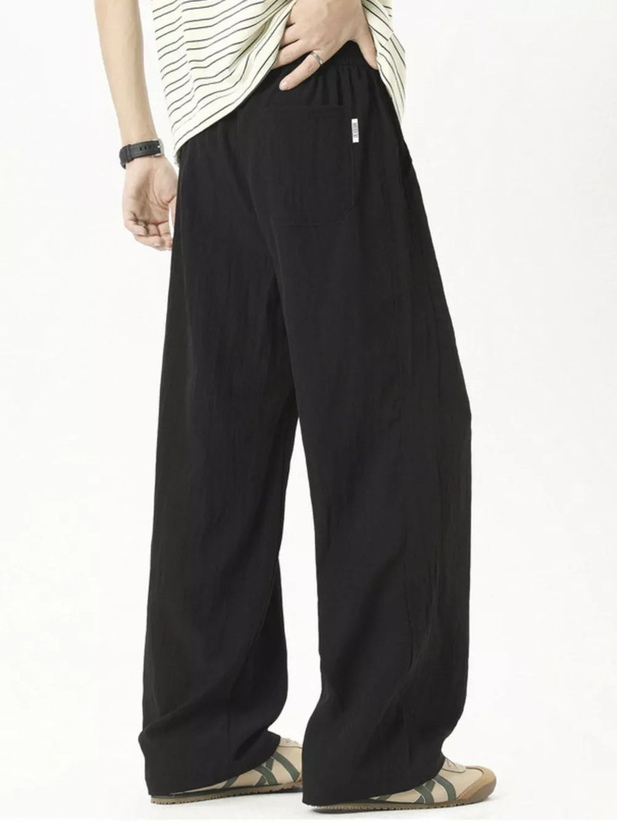 Men's black track pants with a drawstring waist and relaxed fit.