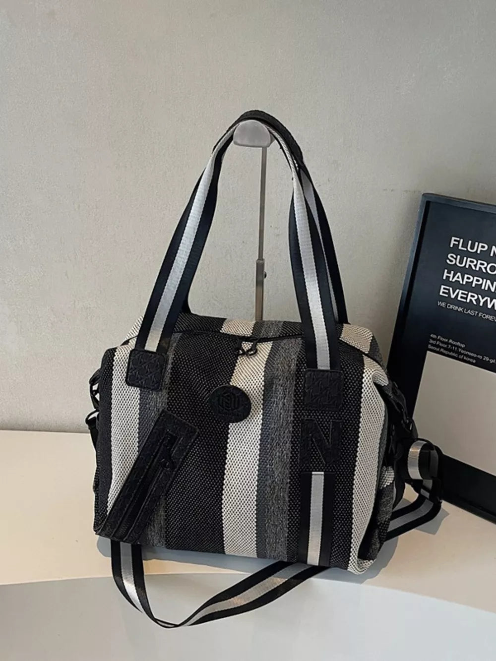 Chic striped medium duffle bag with black and white stripes and a detachable strap.