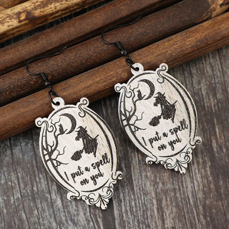 Black wood drop earrings with witch and moon graphic and text I put a spell on you