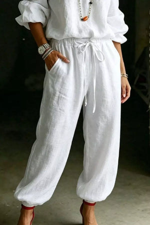 White cotton drawstring pants with pockets, part of a two-piece set.