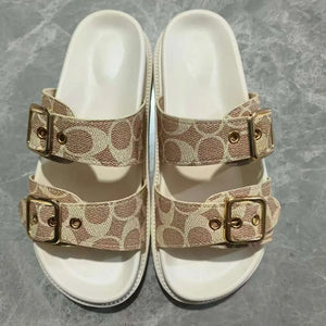 Buckle detail logo slide sandals in beige with double straps and gold hardware.