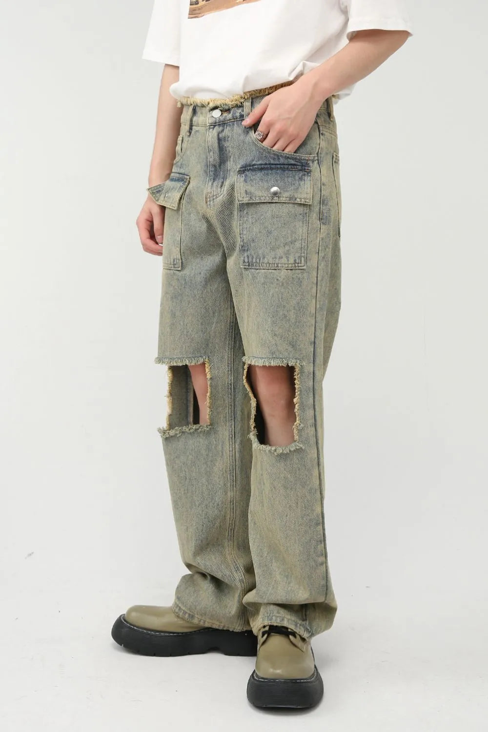 Distressed medium wash denim cargo jeans with large knee cut-outs and frayed edges.