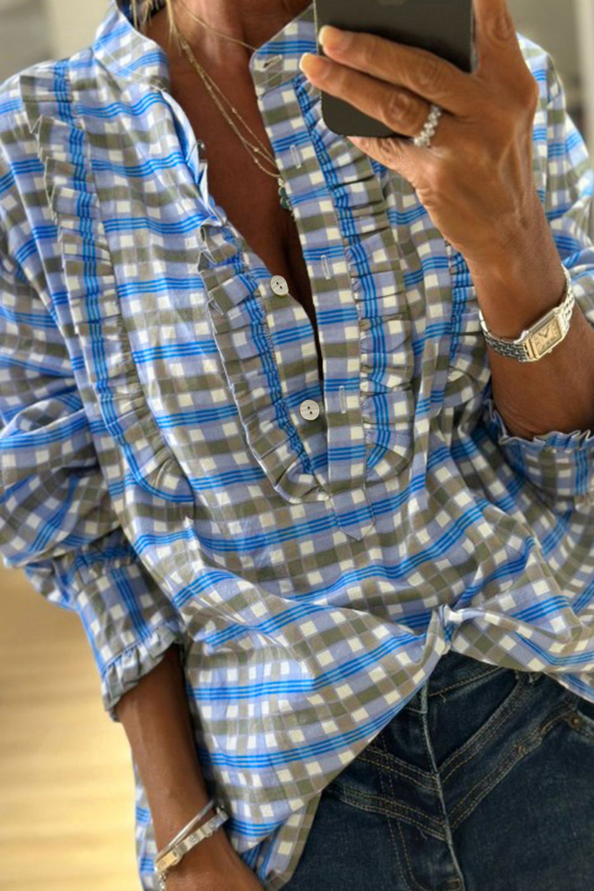 Blue plaid button-down blouse with frilled detail and buttoned neckline.