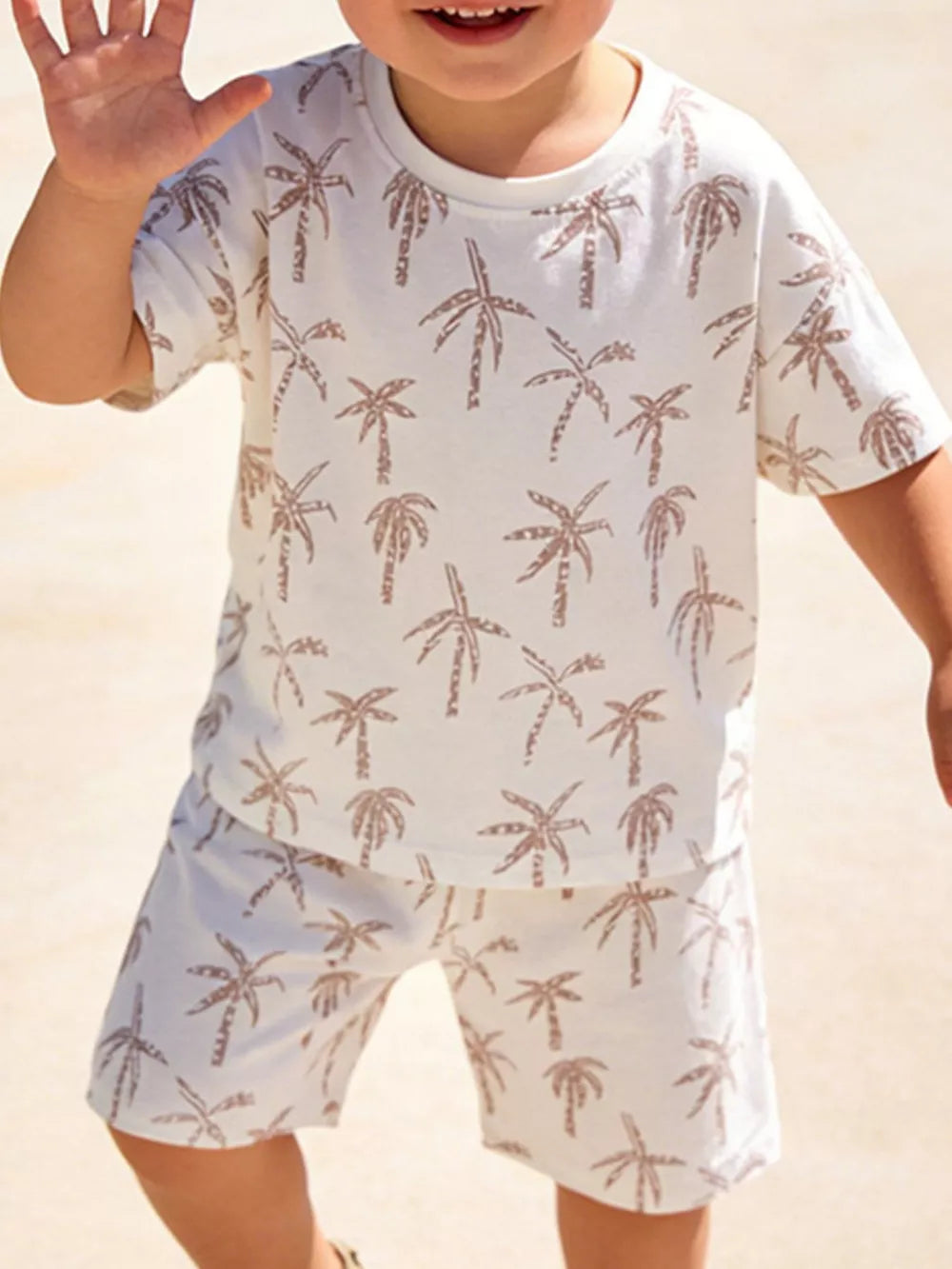 Boys' beige cotton two-piece set with tropical palm print, short sleeves and shorts.