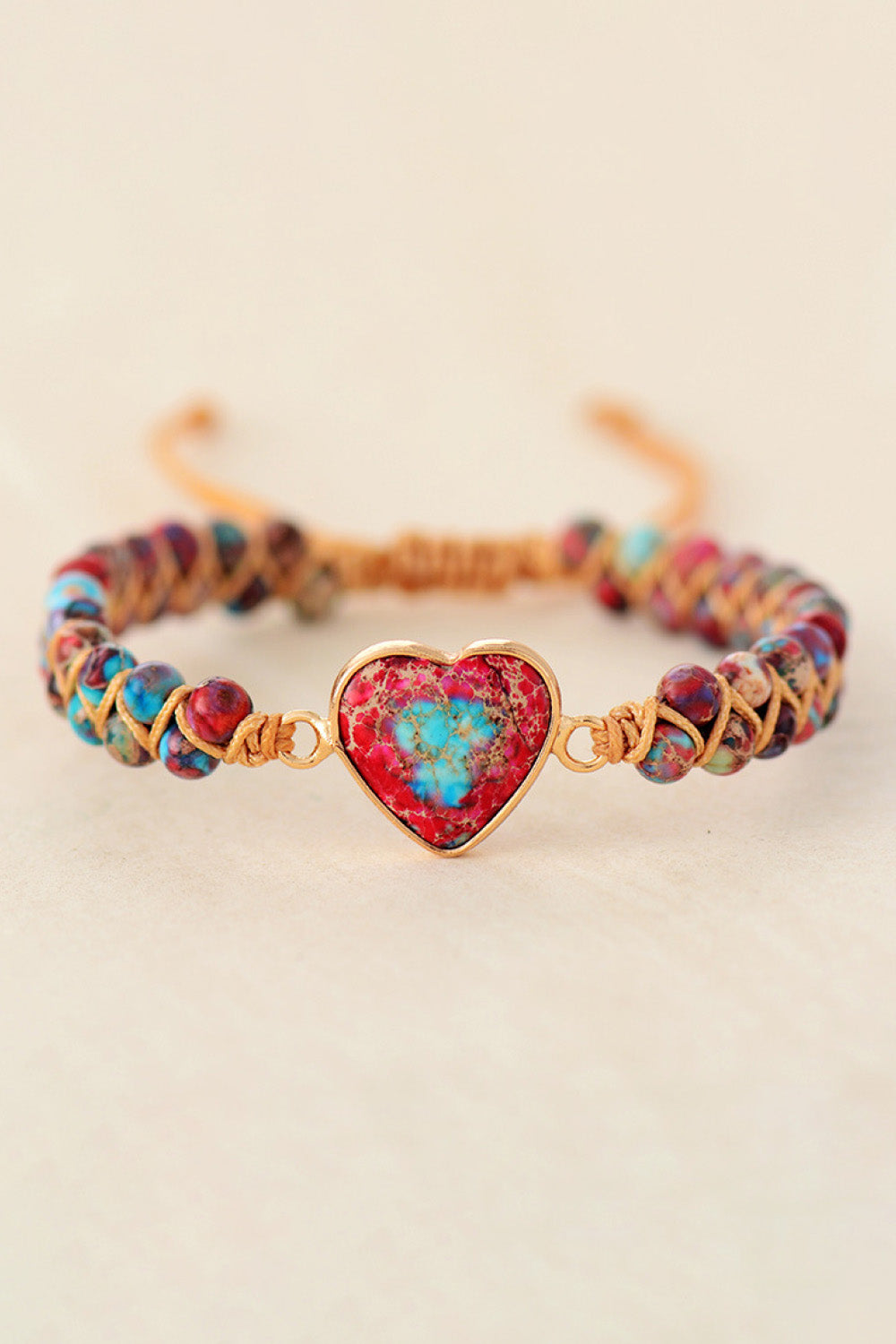 Multicolor beaded bracelet with a red and blue heart stone centerpiece and gold accents.