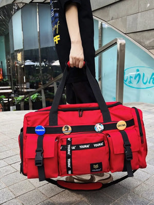 Red duffel bag with multiple pockets, straps, buckles, and decorative pins.