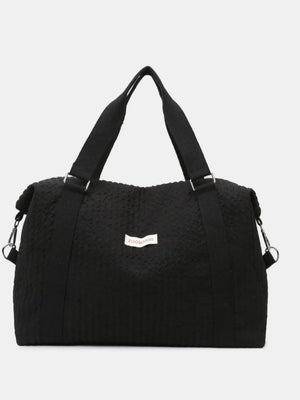 Black waffle-weave weekend bag with silver hardware and adjustable strap.
