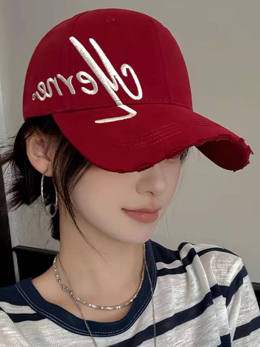 Red baseball cap with white embroidered script logo and distressed brim