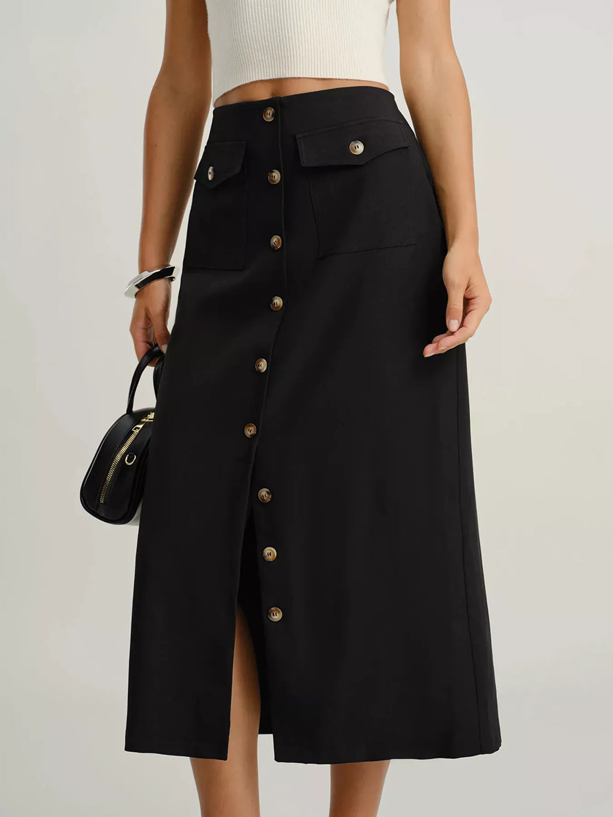 Black midi skirt with button front, flap pockets, and a front slit.