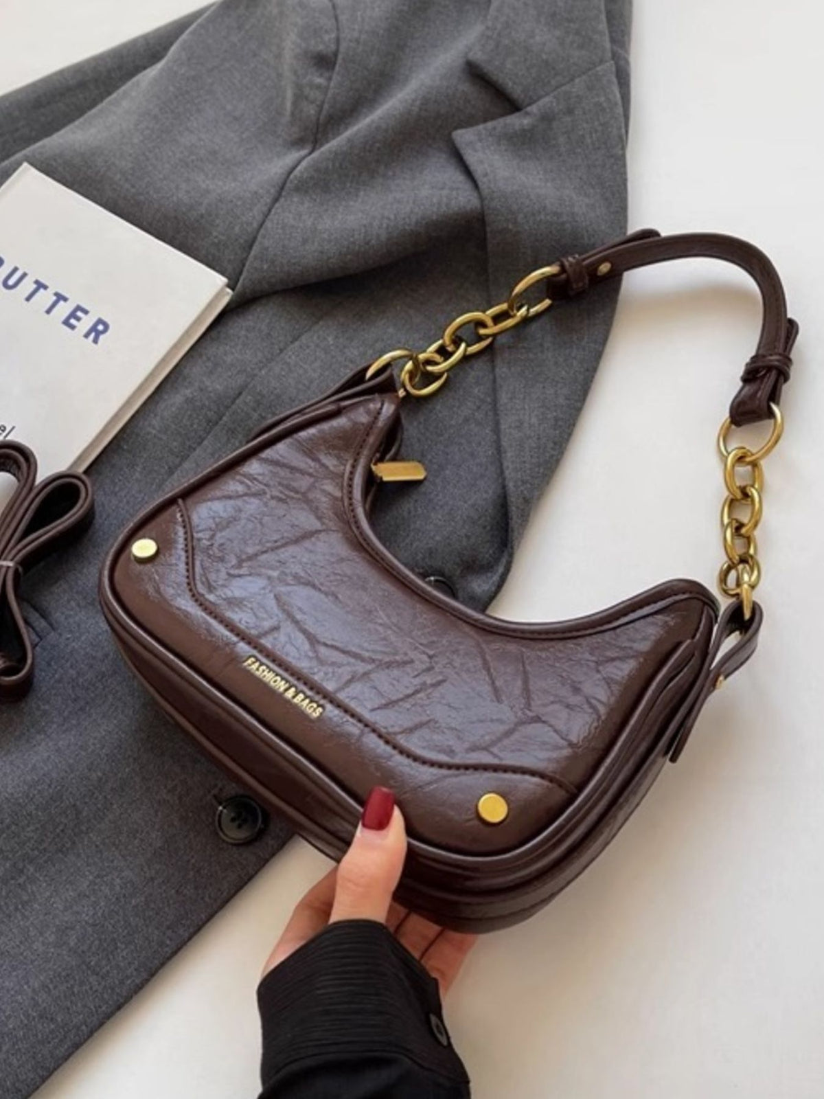 Coffee color crescent shoulder bag with chunky chain accent and textured finish.