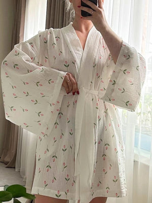White cotton robe with pink floral print, wide sleeves, and tie waist.