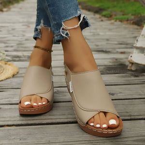 Khaki open-toe wedge sandals with crisscross straps and white stitching detail.