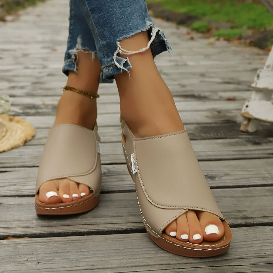 Khaki open-toe wedge sandals with crisscross straps and white stitching detail.