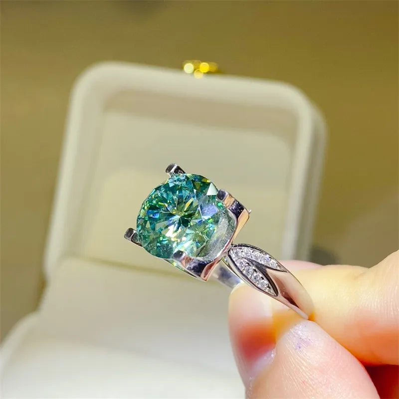 Silver ring with sculpted band and large green moissanite solitaire.