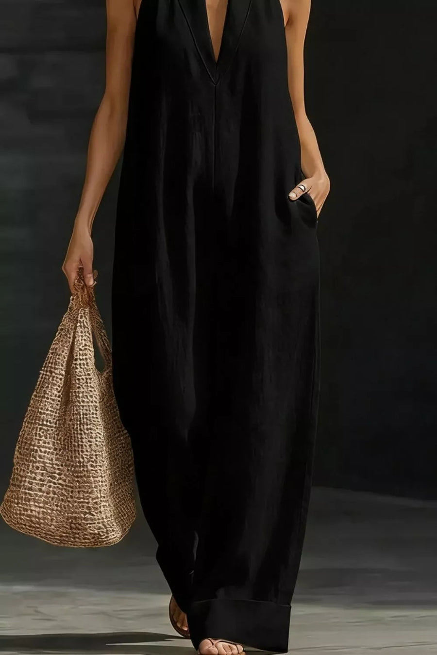 Black halter-neck maternity jumpsuit with pockets, v-neck, and wide legs.