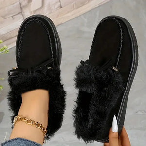 Black suede loafers with shearling trim and decorative bow detail.