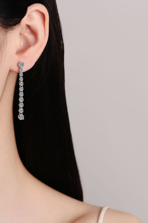 Silver linear drop earrings with moissanite stones cascade from an earlobe.