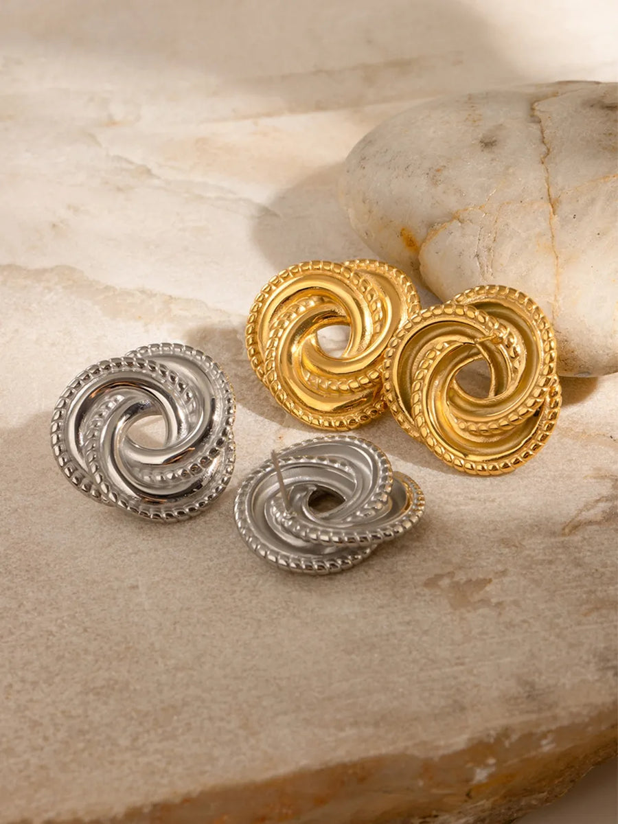 Golden and silver swirl knot stud earrings with textured edges.