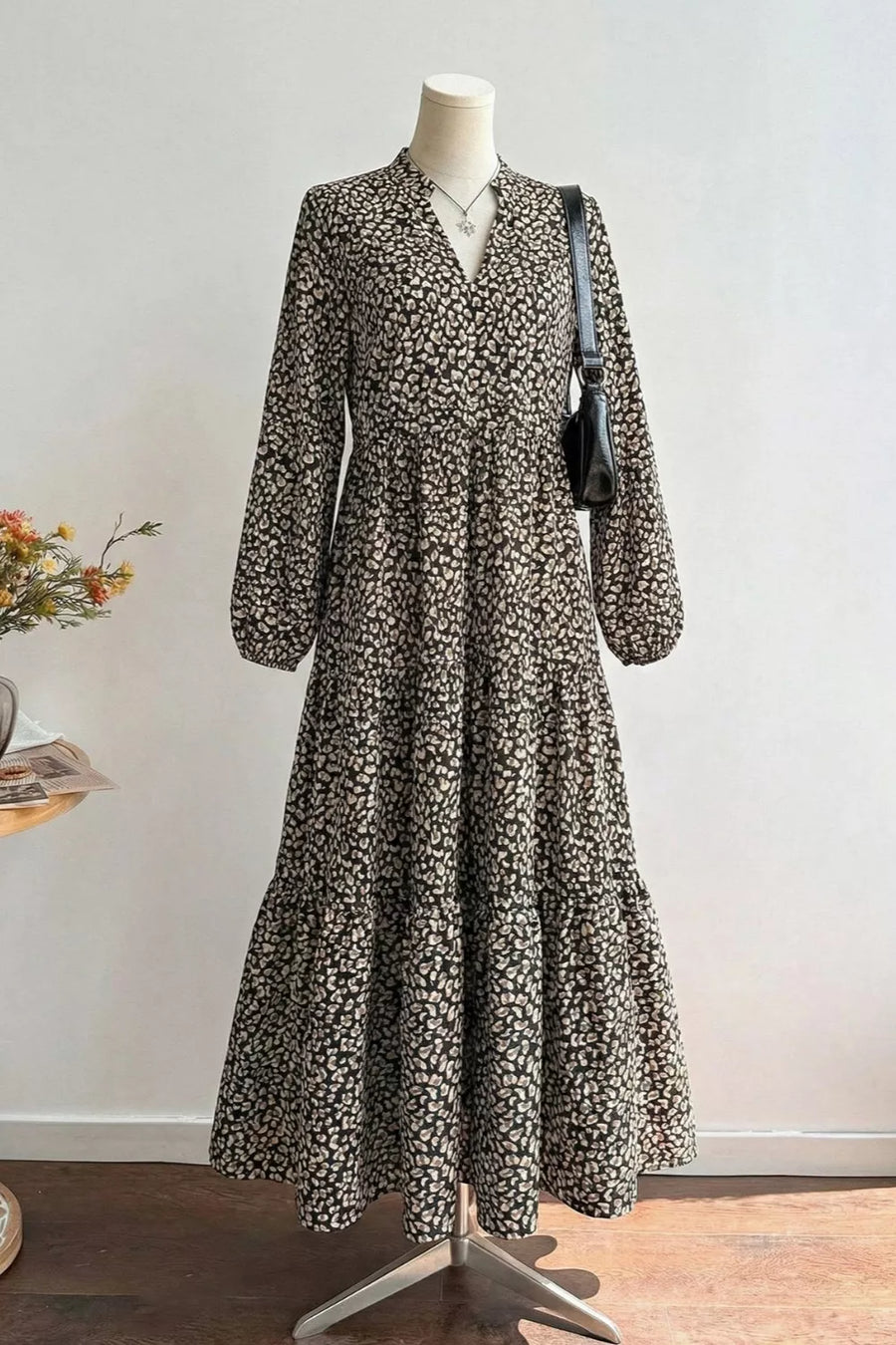 Chic black midi dress with animal print, V-neck, balloon sleeves, and tiered skirt.